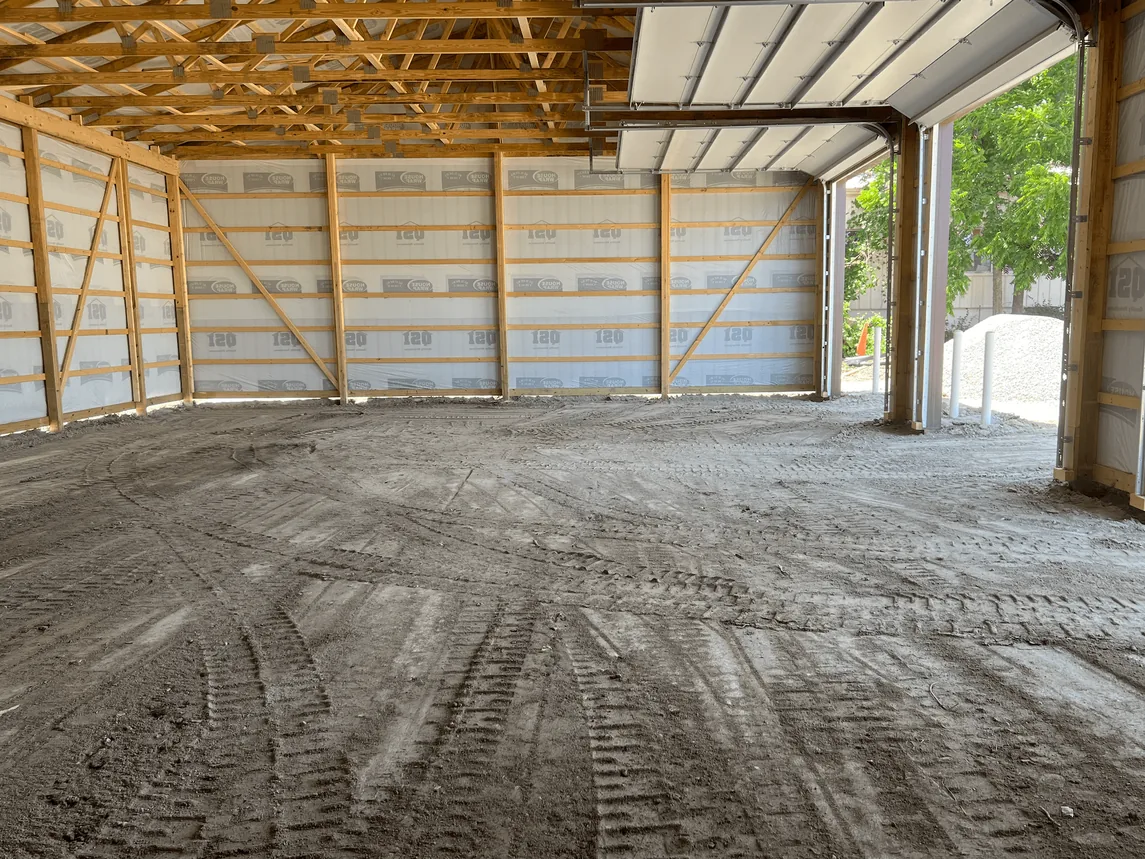 Leveled and rolled gravel pad inside a framed pole building shop, building pads