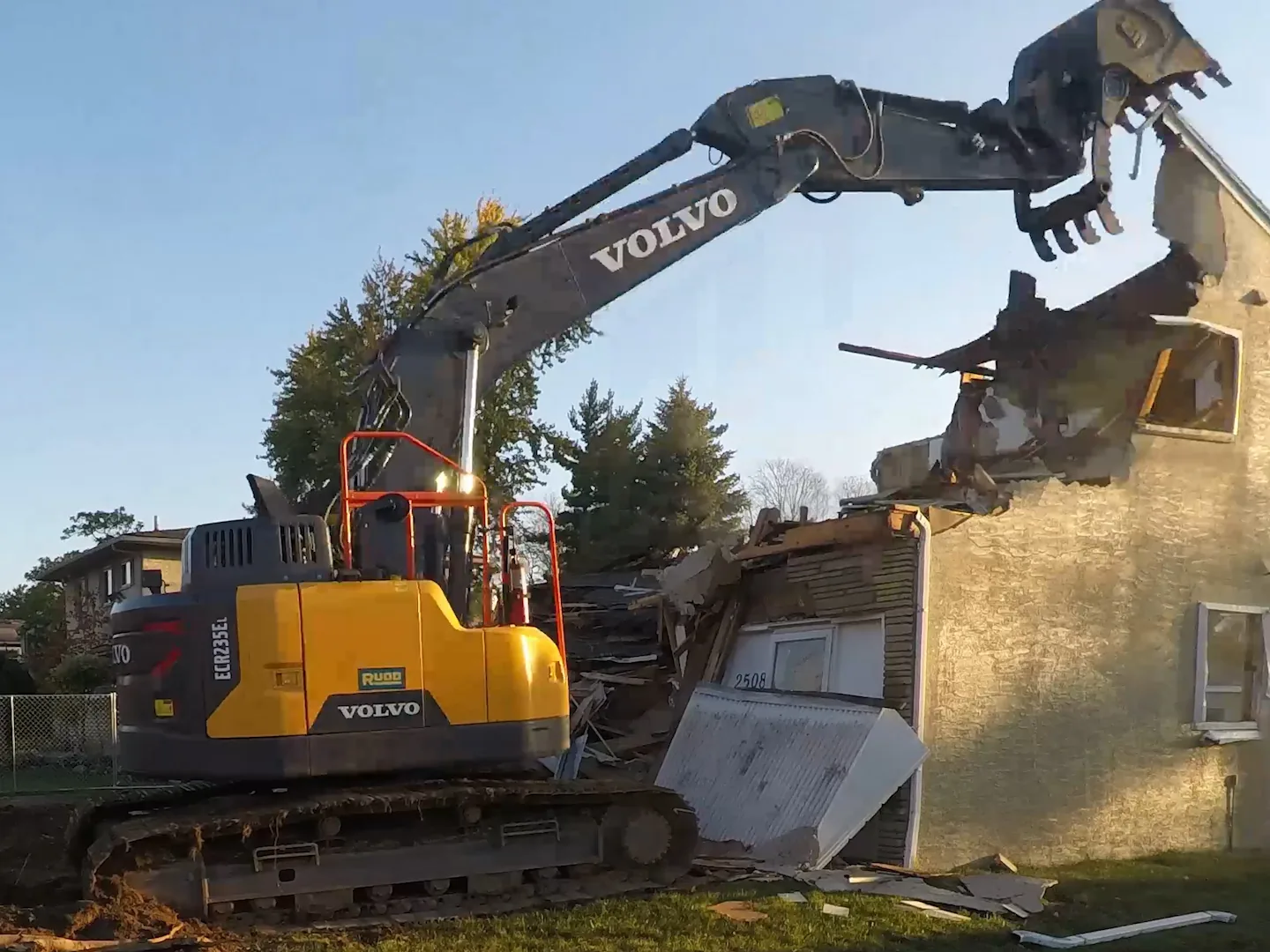 Excavator with a demolition grapple tearing down a two story house, demolition