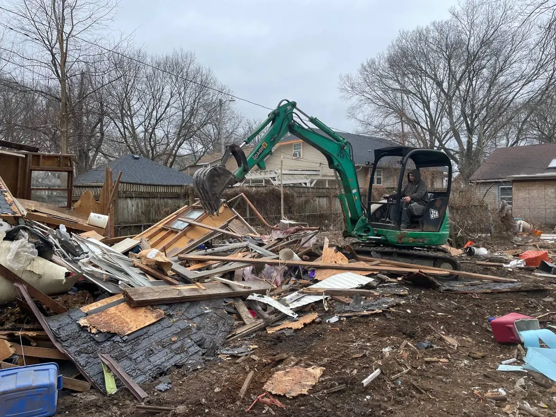Mini excavator piling the debris of a torn down backyard shed, demolition