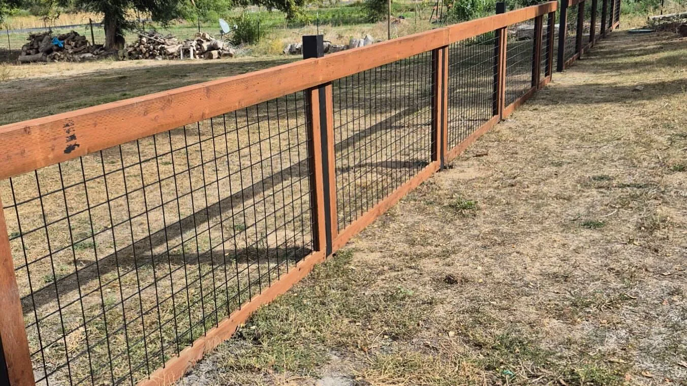 Wood frame fence with wire panels along a dry yard, general contracting