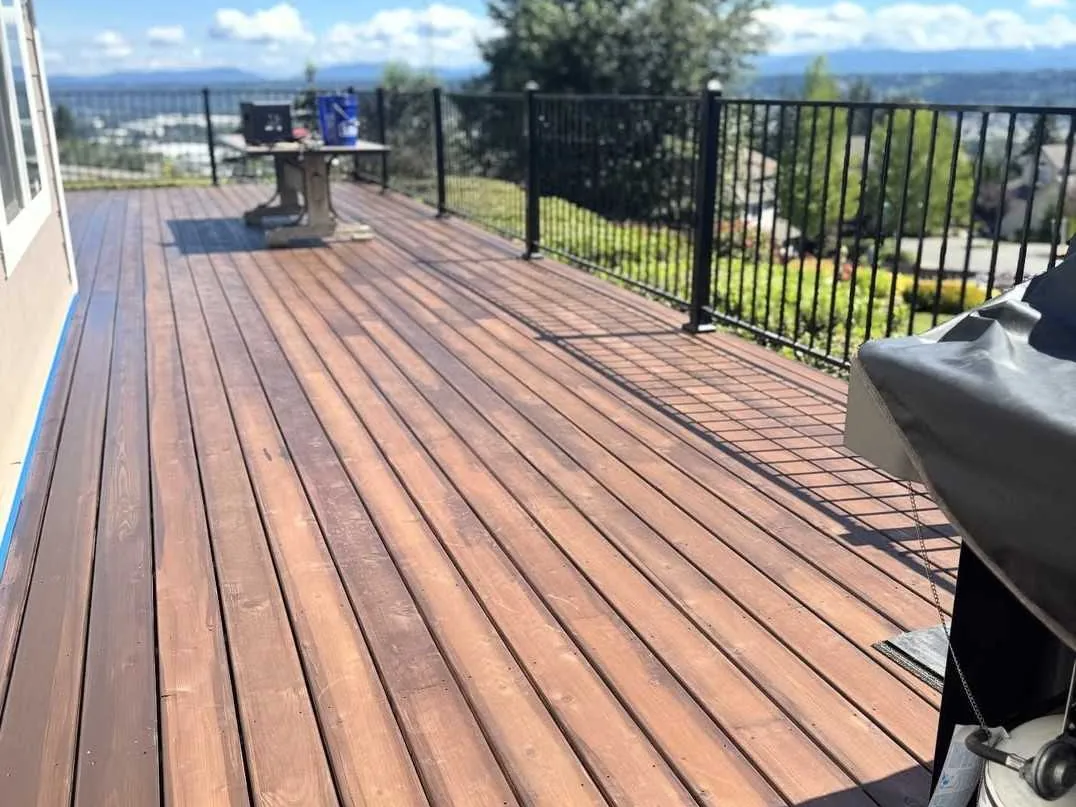 Restained wood deck with a black metal railing, general contracting