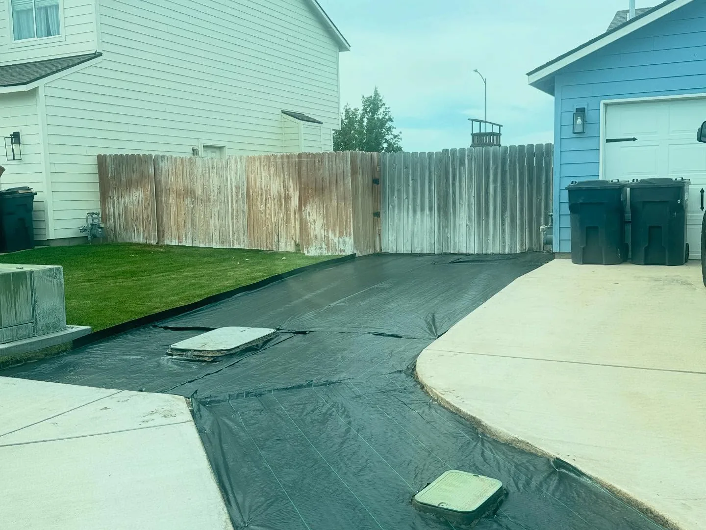 Black landscape fabric laid over a graded strip before the gravel, grading