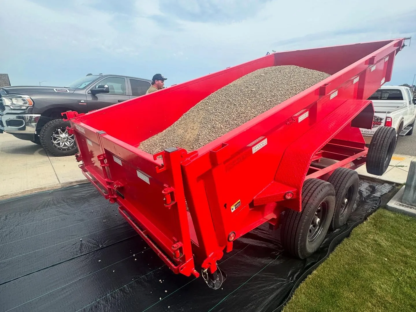 Red dump trailer loaded with gravel raised over landscape fabric, mass excavation