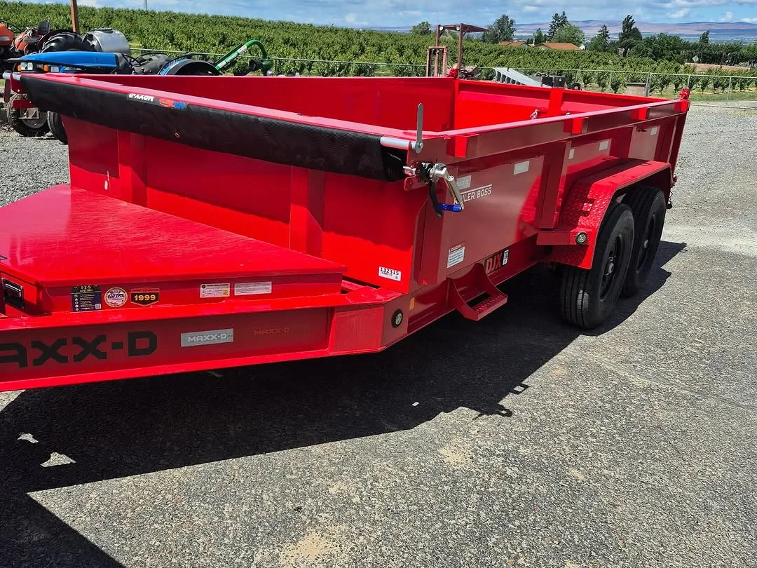 Red dump trailer parked on gravel with an orchard behind, mass excavation