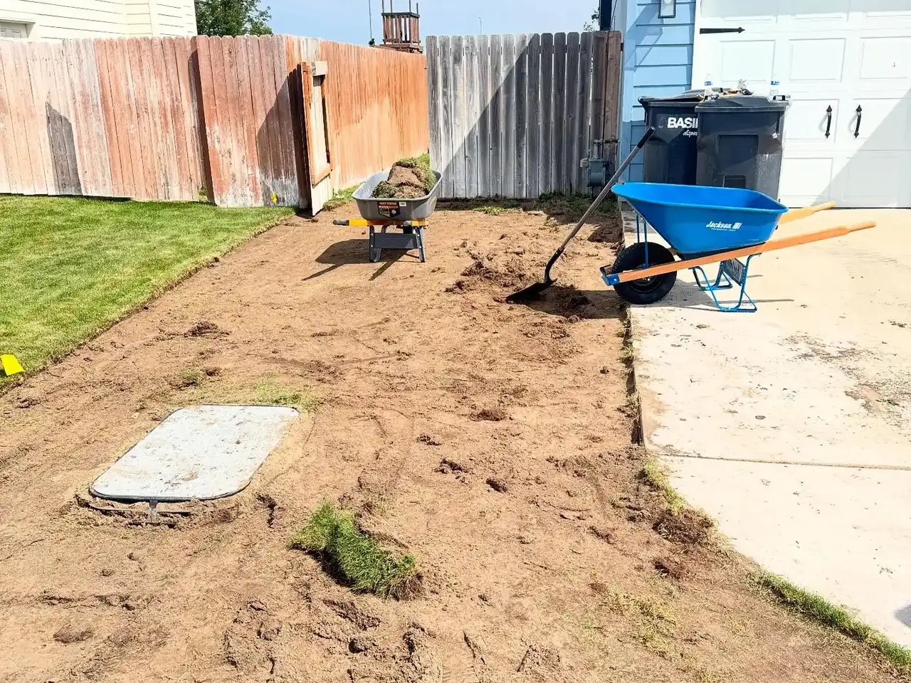 Ground cleared and leveled to bare dirt beside a new concrete slab, orchard removal